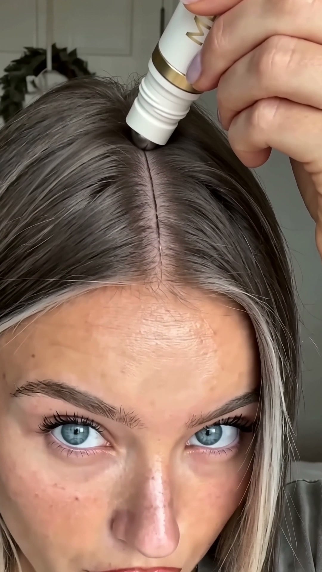 MEORI stainless roller placed directly against an exposed blonde scalp part